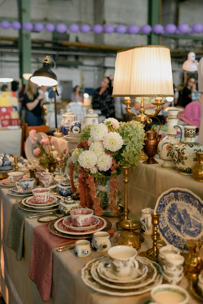 A display of vintage pottery and lamps at an antique market indoors.