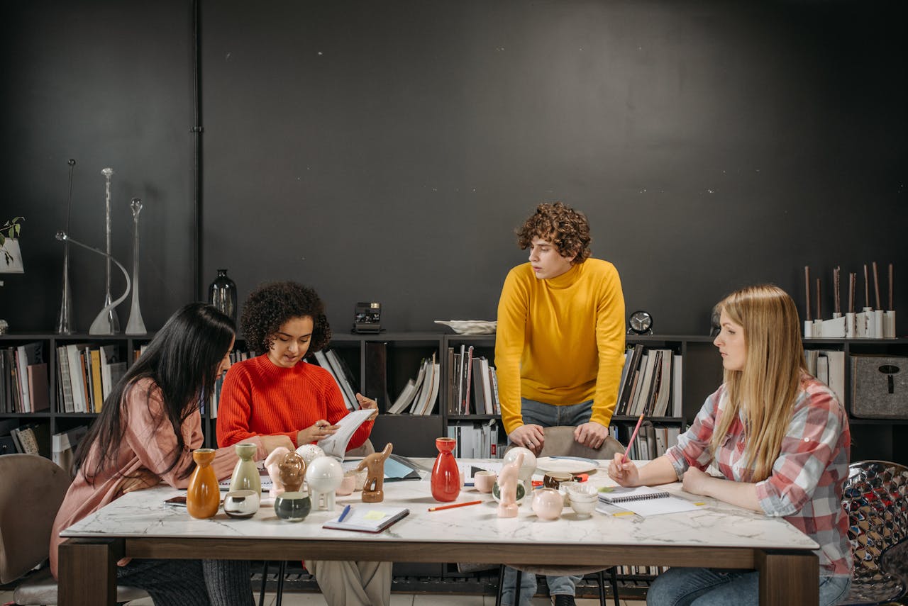 A diverse group in an office setting brainstorming with ceramic products on a table.